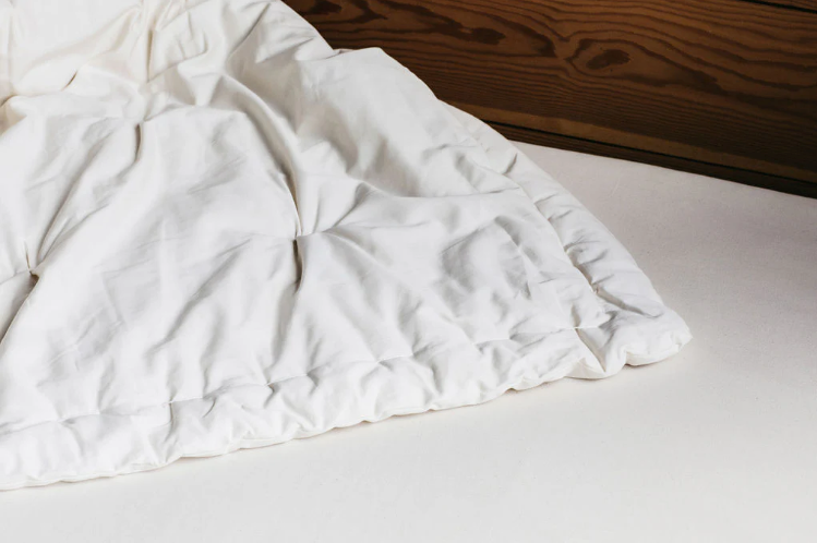 Stitched with care, you get warmth, temperature regulation, and breathability in this signature handmade product. Designed and handcrafted for comfort and coziness, our quilted comforters are made from domestically sourced premium eco wool encased in an organic cotton sateen shell. Hand-tufted and stitched around the perimeter so the wool batting stays in place. Now with corner ties for securing into your duvet cover. These comforters naturally regulate body temperature while wicking away moisture, ensuring