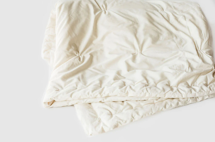 Stitched with care, you get warmth, temperature regulation, and breathability in this signature handmade product. Designed and handcrafted for comfort and coziness, our quilted comforters are made from domestically sourced premium eco wool encased in an organic cotton sateen shell. Hand-tufted and stitched around the perimeter so the wool batting stays in place. Now with corner ties for securing into your duvet cover. These comforters naturally regulate body temperature while wicking away moisture, ensuring