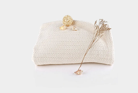 Experience year-round comfort with our Organic Waffle Weave Blanket, featuring a soft, lightweight design for cozy versatility. Crafted from GOTS certified organic cotton, this blanket offers both style and sustainability. Its loose waffle weave provides enhanced flexibility and breathability, perfect for all seasons. Whether draped over your bed or used as a stylish throw, its natural ivory color and hemmed edges add a touch of elegance to any space. Plus, it’s conveniently machine washable for easy care.