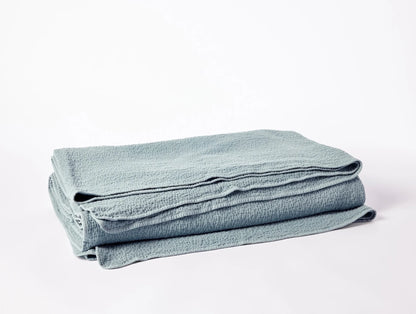 Crafted in Portugal from exceptionally fine yarns, this matelass√© blanket pairs a light, lofty feel with a high performance, stitched texture. Inspired by quilted kantha cloth, each blanket is stonewashed to enhance the raw beauty and softness of rumpled organic cotton. Finished with a simple bound edge for heirloom detail and effortless layering.