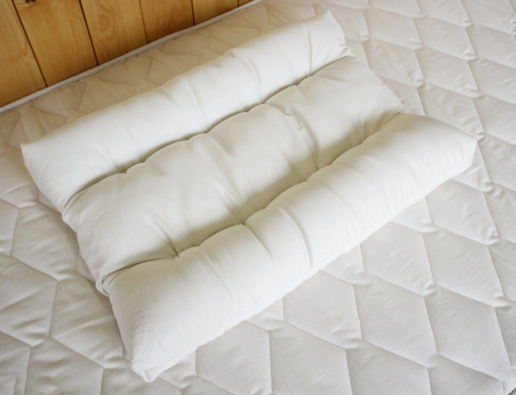 Developed in partnership with a chiropractic physician, this unique design allows your head to rest on a flat surface while your neck stays properly supported and in cervical alignment with your spine.

With a neck bolster along each long edge, one stuffed slightly more than the other, you can choose the exact amount of support you need. Made with Premium Eco Wool and 100% Organic Cotton, you also get the added benefits of temperature regulation and dust-mite resistance.