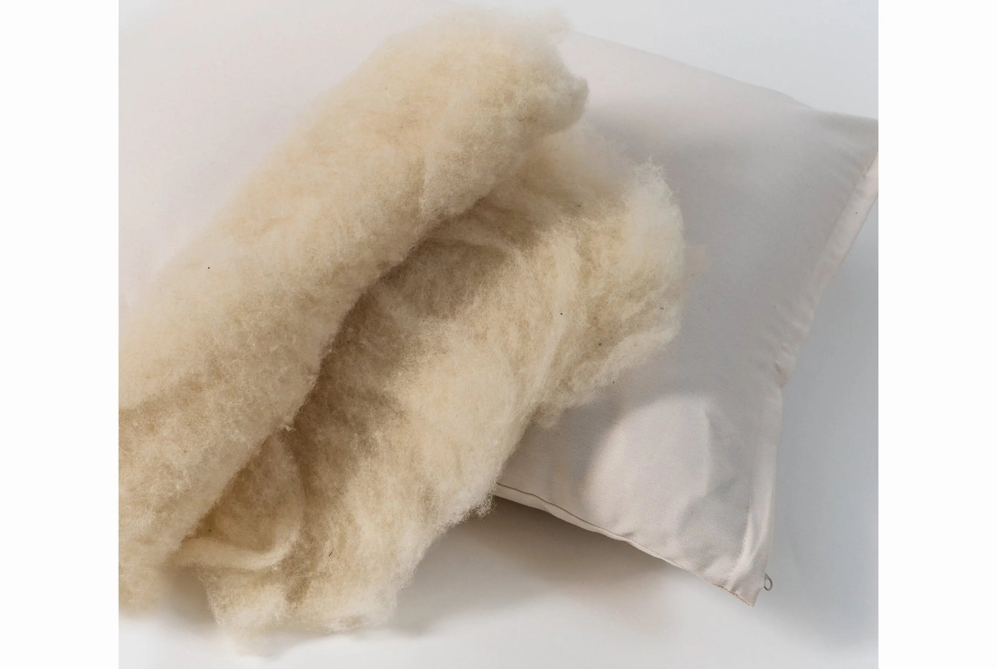 This pillow is made from certified organic wool and is covered in organic cotton sateen. Wool will not compress as much over time as an organic cotton pillow. Wicks away moisture on hot nights to help keep you cool and insulates on cool nights. Spot clean only. Comes with a zipper so you can add or remove filling.