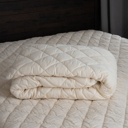 The washable wool mattress pad is made of our American Dream Wool and quilted using organic cotton on both sides. It provides excellent protection to your mattress. The washable wool pad is skirted with organic cotton knit and features an 18" pocket. It will keep your mattress looking newer longer. Made in the USA.